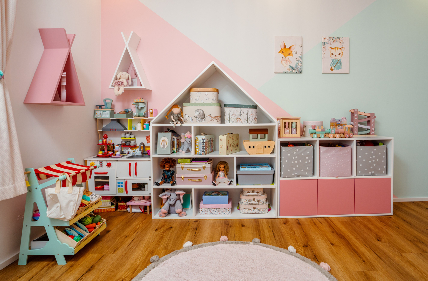 A toddler playroom with a soft circular rug anchoring the floor zone, low-height storage, and child-scale furniture arranged with clear sightlines and accessible play area.