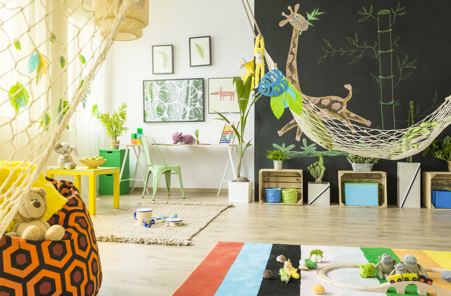 A bright playroom with open floor space, a suspended hammock, and a geometric beanbag chair showing a movement-friendly indoor layout suitable for gross motor activities for preschoolers