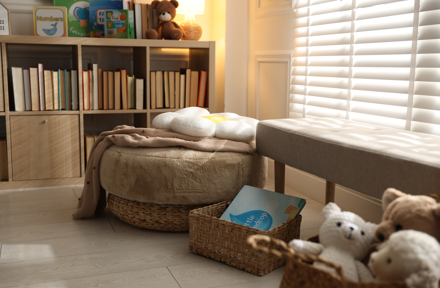 A children's reading nook corner with a low bookshelf and plush floor seating, demonstrating a kids bedroom reading nook with books at child height
