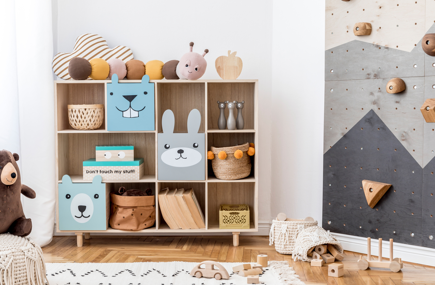 Indoor gross motor activities for preschool - a children's playroom with a low indoor climbing wall, wooden shelving with baskets, and open floor space cleared for active movement